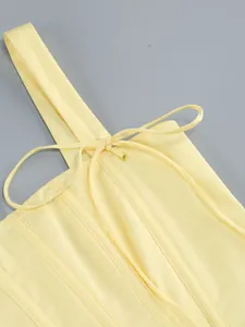 Primo piano della struttura a stecche e del laccio frontale di questo bustier giallo