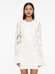 Close-up detail of elegant white lace mini dress with floral embroidery and ruffle sleeves
