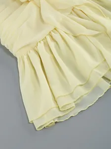 Close-up detail of yellow chiffon ruffles and pleated hem on an elegant dress