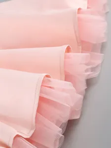 Detail showing the layered hem of a pink party dress with delicate mesh and tulle lining
