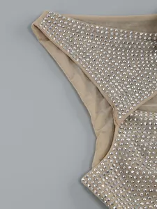 Nahaufnahme der silbernen Strasssteine auf beigem Mesh-Stoff eines sexy Cut-out-Kleides.