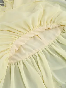 Close-up detail showing the elegant ruffled texture and soft chiffon fabric of a yellow dress