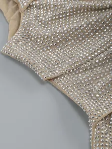 Detaillierte Nahaufnahme von silbernen Strasssteinen auf beige Netzstoff für ein Kleid