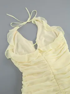 Close-up of sexy light yellow halter neck dress with elegant ruffle trim and ruched detailing