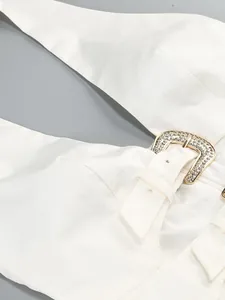 Close-up of white halter dress with rhinestone-encrusted gold metal buckle detail.