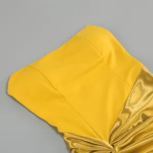 Close-up detail of vibrant yellow evening dress featuring metallic gold draped fabric texture