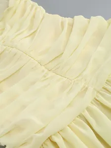 Detail view of the delicate ruching and pleated texture on a pale yellow chiffon dress.
