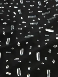 Close-up of black mesh fabric featuring sparkling silver rhinestones for evening dress.
