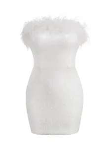 Detalle elegante de vestido ajustado con lentejuelas blancas y ribete de plumas de avestruz
