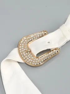Close-up of sparkling rhinestone horseshoe buckle on white halter dress