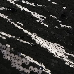 Dettaglio ravvicinato di tessuto con paillettes bianche e nere per un abito da sera.