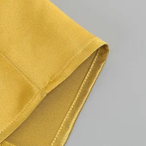 Close-up detail of yellow satin fabric and stitching on a French style maxi dress