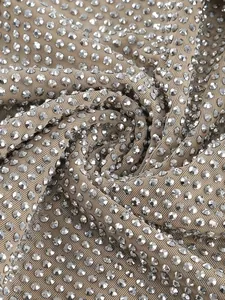 Nahaufnahme von beigem Netzstoff mit glänzenden Silber-Strasssteinen für Partykleid