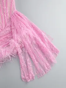 Detailed close-up showing pink floral lace and soft feather trim on a sheer corset gown