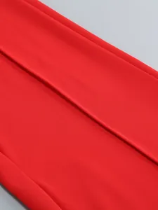 Close-up detail of red fabric showing the seam and texture of elegant wide-leg trousers.