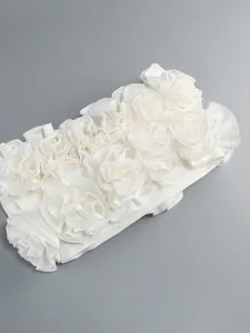 Dettaglio ravvicinato di applicazioni floreali in tessuto 3D su un abito bianco fasciante