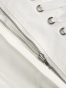 Dettaglio macro della zip argento e occhielli su tessuto per abito bianco elegante.