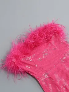 Primer plano detallado de un vestido de lentejuelas fucsia con ribete de plumas de avestruz