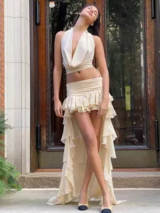 Close-up detail of sexy two-piece set with halter top and layered ruffle skirt in beige.
