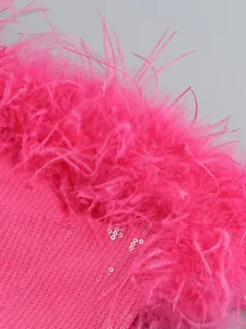 Primer plano de vestido fucsia de lentejuelas con lujoso adorno de plumas de avestruz