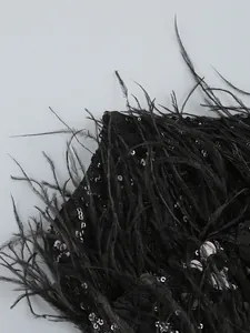 Close-up detail of luxurious black sequins and ostrich feather trim on an evening dress