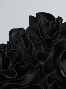 Primo piano dell'elegante dettaglio a balze floreali 3D nere su un abito da sera di lusso