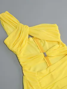 Detailed close-up of a yellow one-shoulder knotted mesh dress with rhinestone buckle.