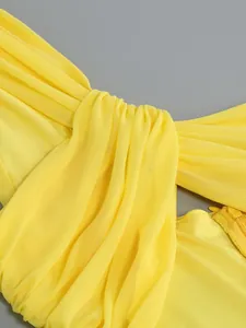 Detailed view of the twisted knot and ruched mesh fabric on a yellow dress.