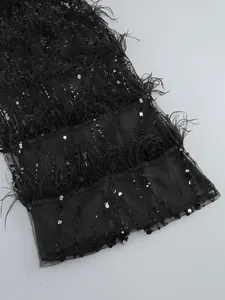Close-up detail showing exquisite black sequins and ostrich feathers on an elegant dress.