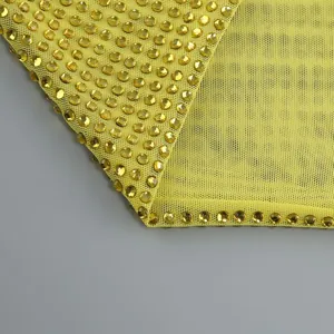 Detaillierte Makroansicht gelber Strassverzierungen auf dem Netzgewebe eines eleganten Kleides