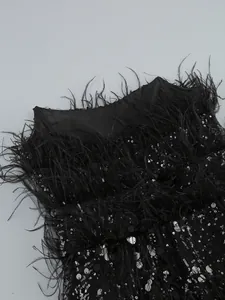 Close-up detail of black sequined evening dress with lush ostrich feather trim neckline