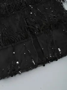 Close-up detail of black sequin and ostrich feather trim on an elegant evening dress.