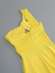 Detail view of yellow one-shoulder ruched dress showing twisted neckline and pleats