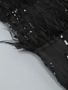 Close-up detail showing black sequins and ostrich feathers on a mesh fabric evening dress