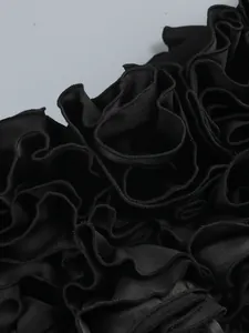 Primo piano del complesso orlo a fiori con volant neri sull'elegante abito da sera sexy