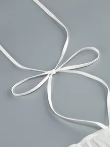 Primer plano detallado del fino tirante de un vestido halter blanco anudado en un lazo elegante