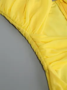 Close-up detail of yellow mesh dress showing elegant ruffled and twisted fabric texture