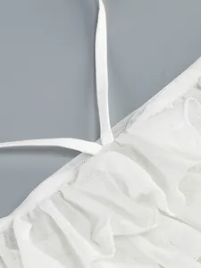 Primer plano detallado de los volantes de malla blanca y los tirantes halter del vestido.