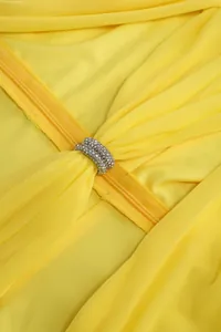Detailed macro view of sparkling rhinestone buckle on yellow pleated cocktail gown fabric