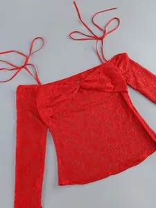 Close-up detail of red floral lace off-the-shoulder top with thin tie-up shoulder straps.
