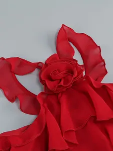 Detailed view of a red sheer halter dress featuring 3D fabric flower and ruffles