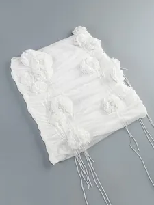 Detalle de los apliques de flores 3D y largas borlas de cinta en vestido blanco