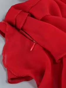 Detail view of red invisible zipper on elegant chiffon dress with ruffled layers