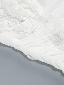 Primer plano de flores de tela 3D blancas y bordados de cuentas en vestido de malla