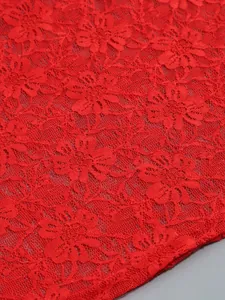 Macro view of vibrant red floral lace fabric showcasing intricate rose patterns and texture