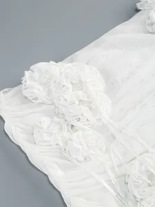 Detalle de vestido de malla blanca con elegantes apliques de flores 3D y cuentas