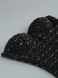 Macro detail showing heavy rhinestone embellishments on a black mesh bandeau party dress.