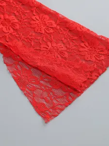 Close-up detail of vibrant red floral lace fabric texture for an elegant evening dress set.