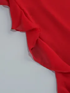 Close-up detail of a vibrant red ruffled lotus leaf edge on a lightweight chiffon dress.