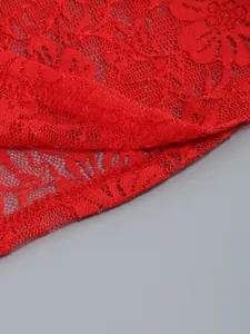 Macro view showing the intricate floral pattern of the vibrant red lace garment fabric